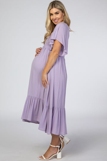 woman wearing a lavender maternity dress with flutter sleeves and a tiered hem, cradling her baby bump