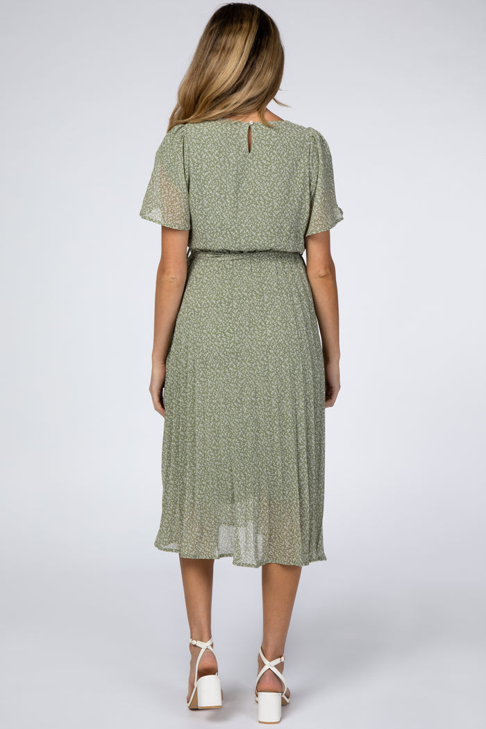 woman wearing a green floral maternity dress with short sleeves and a cinched waist, showing her baby bump from the back