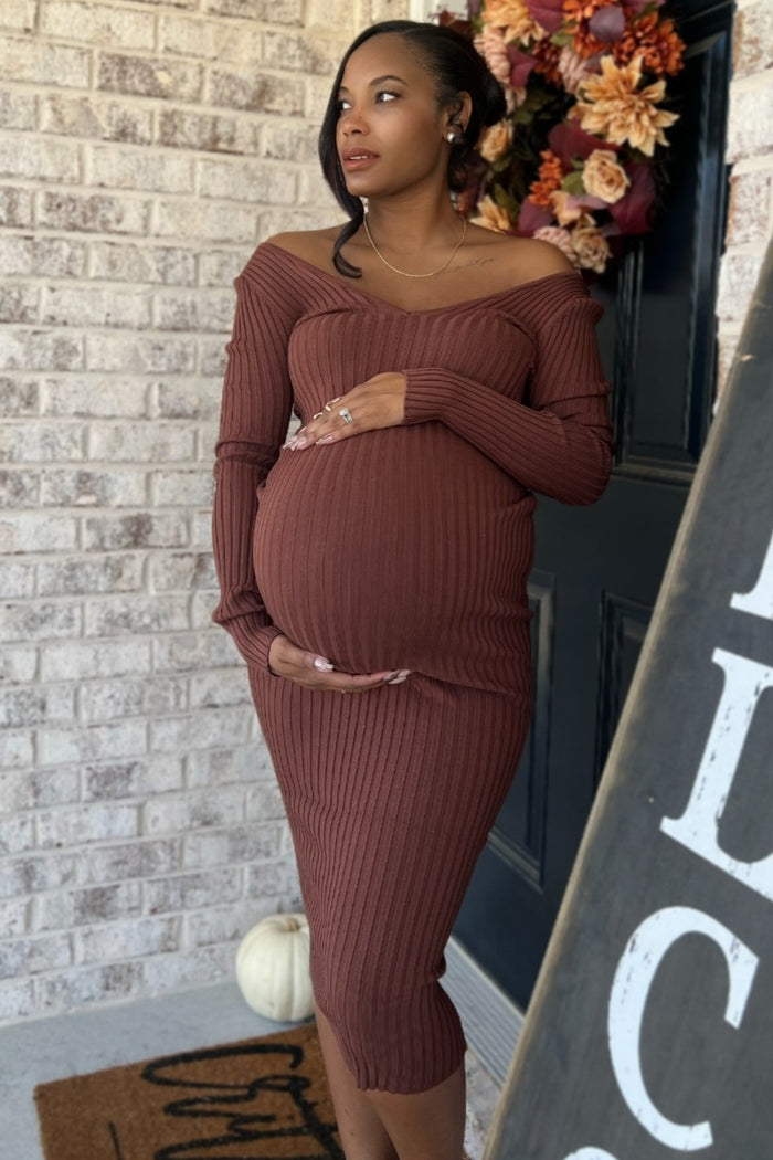 woman wearing a rust-colored off-the-shoulder maternity dress, showcasing her baby bump