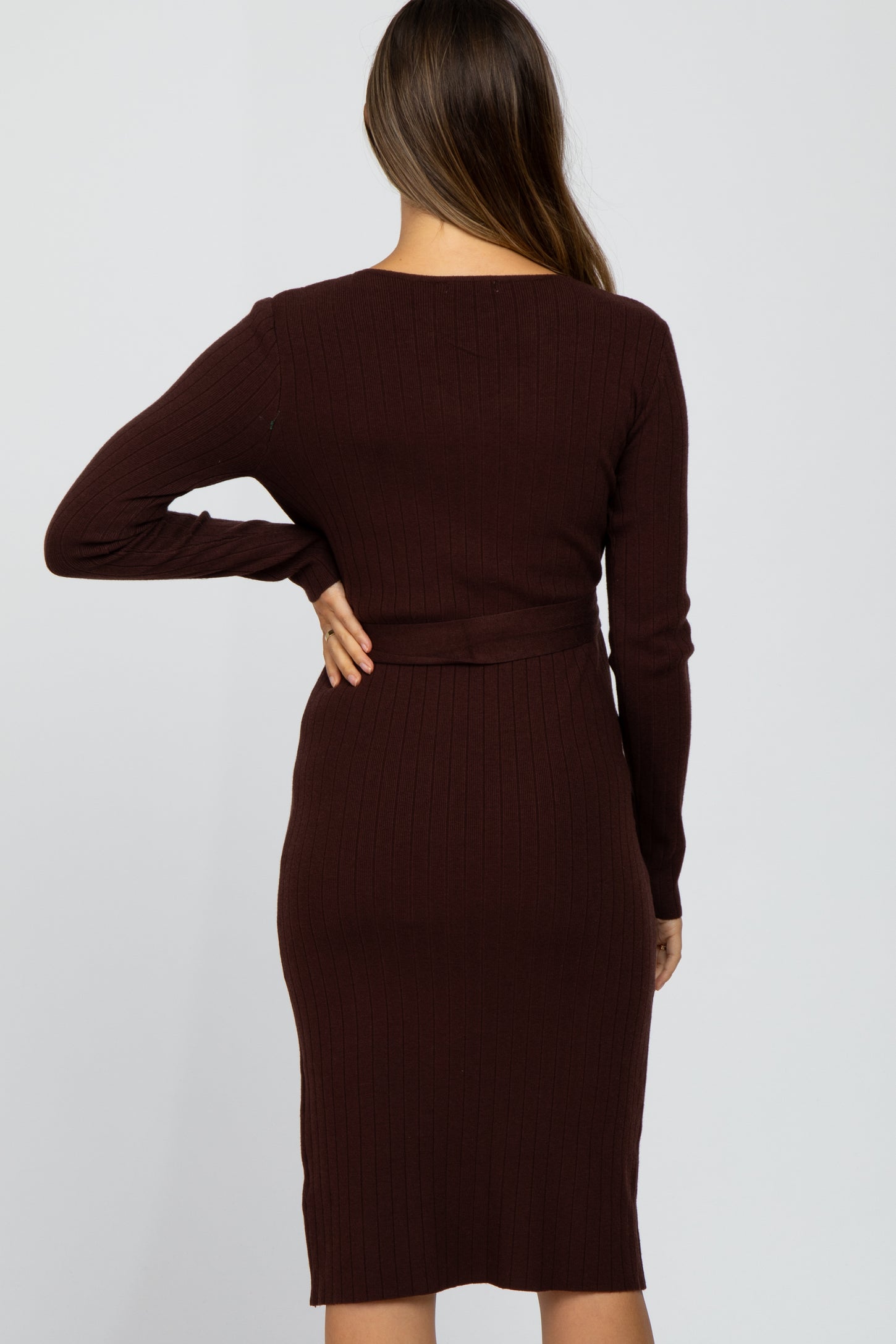 woman wearing a ribbed burgundy maternity dress with long sleeves and a fitted silhouette, showing her back and curves