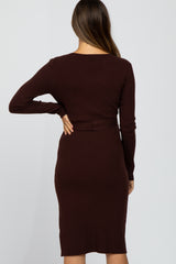 woman wearing a ribbed burgundy maternity dress with long sleeves and a fitted silhouette, showing her back and curves