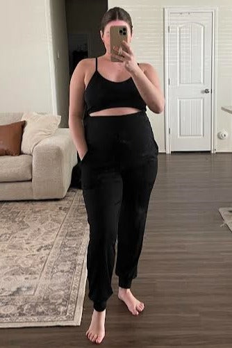 woman taking mirror selfie wearing black two-piece lounge set with crop top and high-waisted joggers