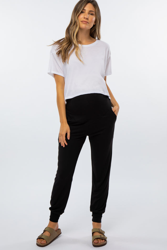 woman wearing a white cropped maternity top and black maternity joggers with pockets