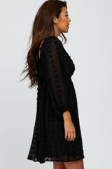 woman wearing a black puff sleeve mini dress with textured polka dots and a relaxed fit