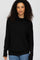 woman wearing a black cowl neck sweater with long sleeves and relaxed fit, paired with light blue jeans