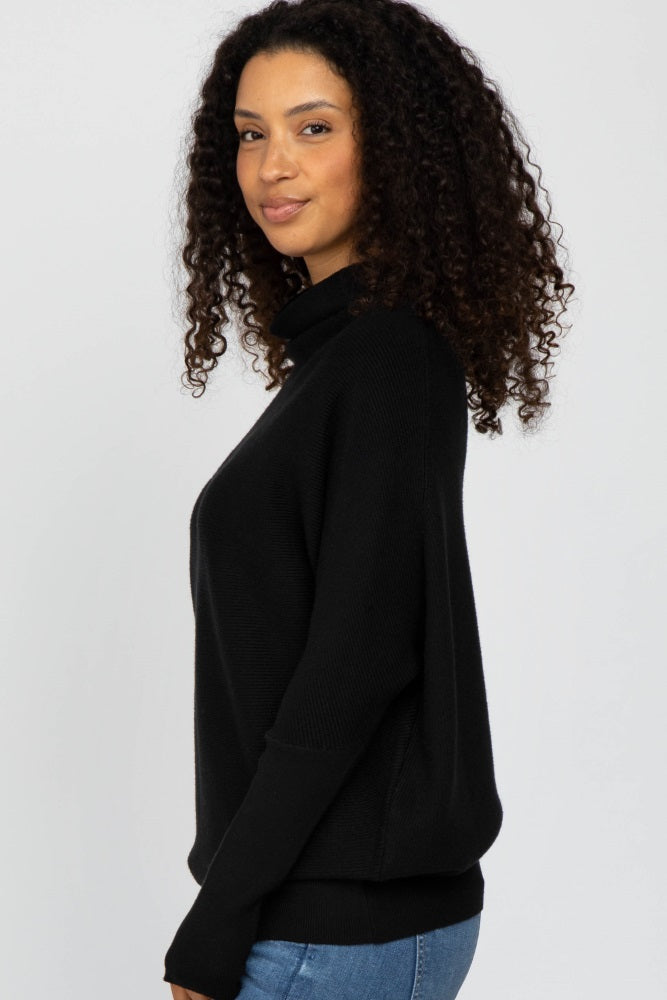 woman wearing a black long sleeve sweater with a relaxed fit and mock neckline, styled with blue jeans