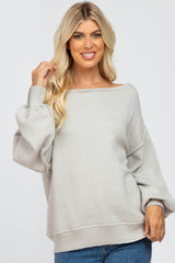 blonde woman wearing a light grey oversized boat neck sweater with balloon sleeves and blue jeans