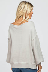 woman wearing a light gray oversized sweater with a wide neck and balloon sleeves, view from the back