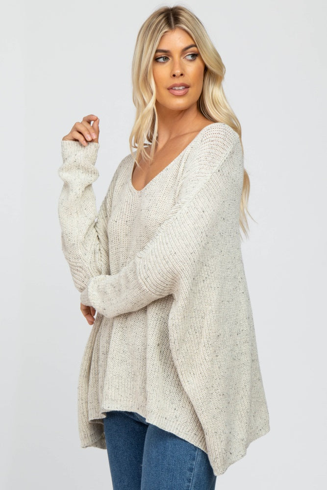 woman wearing a loose-fitting cream v-neck sweater with long sleeves and a relaxed silhouette, paired with blue jeans