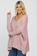 blonde woman wearing a dusty rose oversized v-neck knit sweater and blue jeans