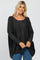 woman wearing a dark gray oversized sweater with a rounded neckline and relaxed fit, paired with blue jeans