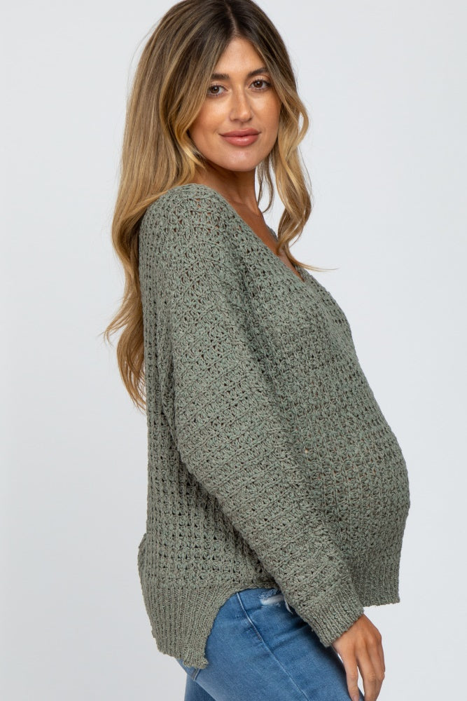 woman wearing a green open knit maternity sweater with a visible baby bump and relaxed fit