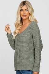 woman wearing a green v-neck knitted sweater with a relaxed fit and long sleeves