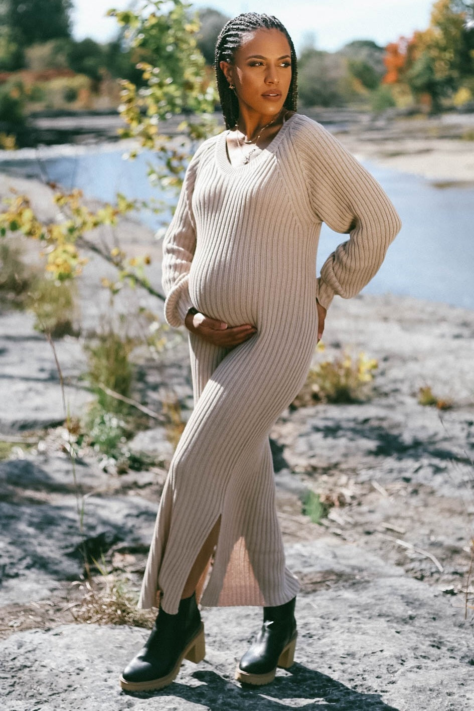 woman wearing a beige ribbed maternity dress with long sleeves, standing outdoors and showing her baby bump