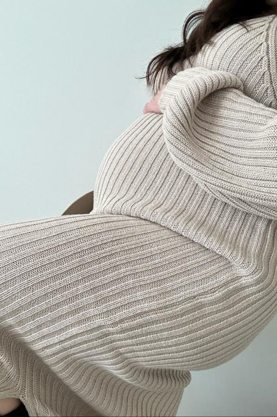 woman wearing a beige ribbed maternity sweater dress with a visible baby bump