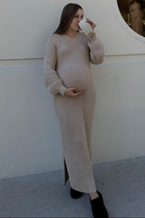 woman wearing a beige ribbed maternity dress and holding her baby bump while sipping from a cup