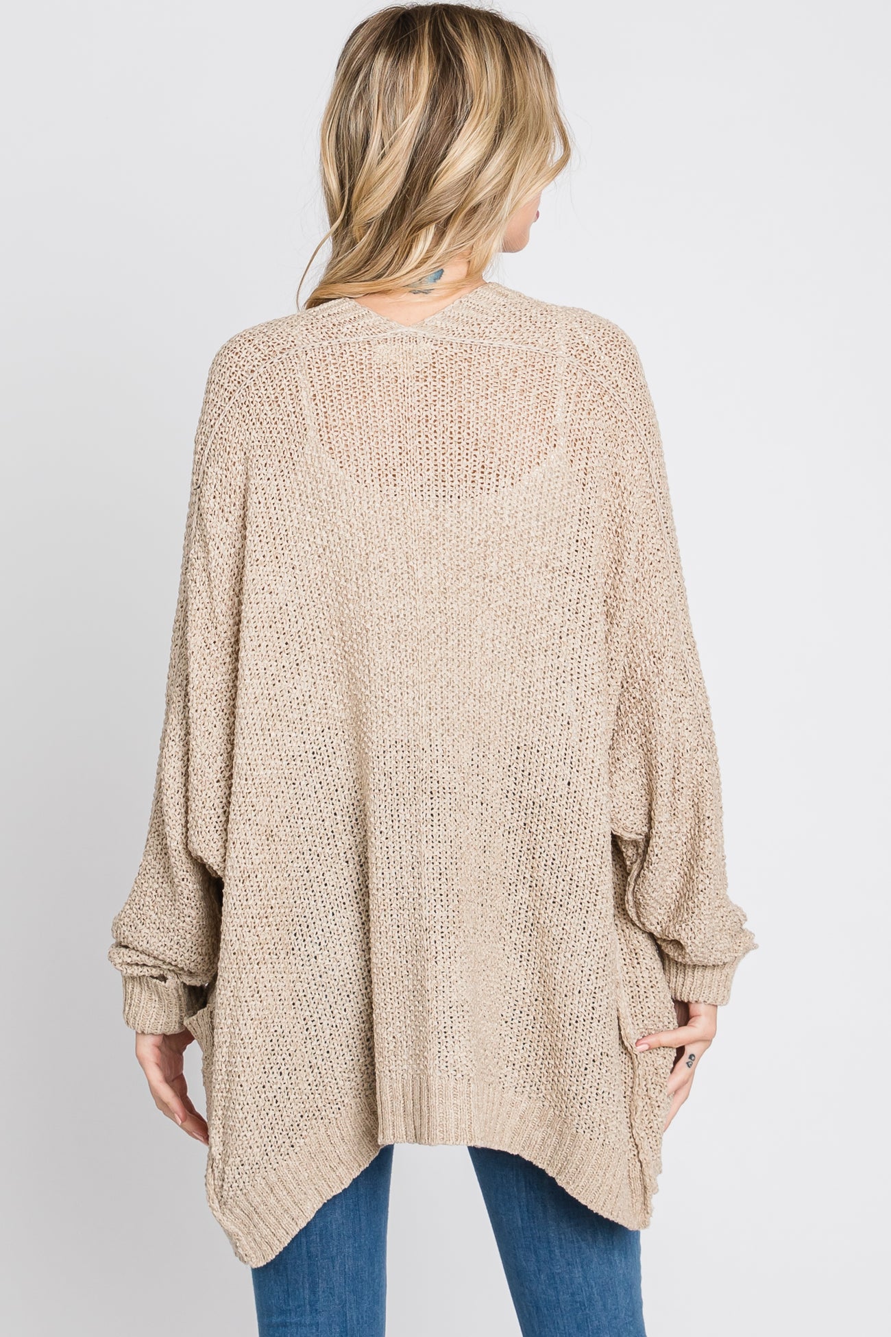 woman wearing a beige oversized knitted cardigan sweater with a loose fit and batwing sleeves