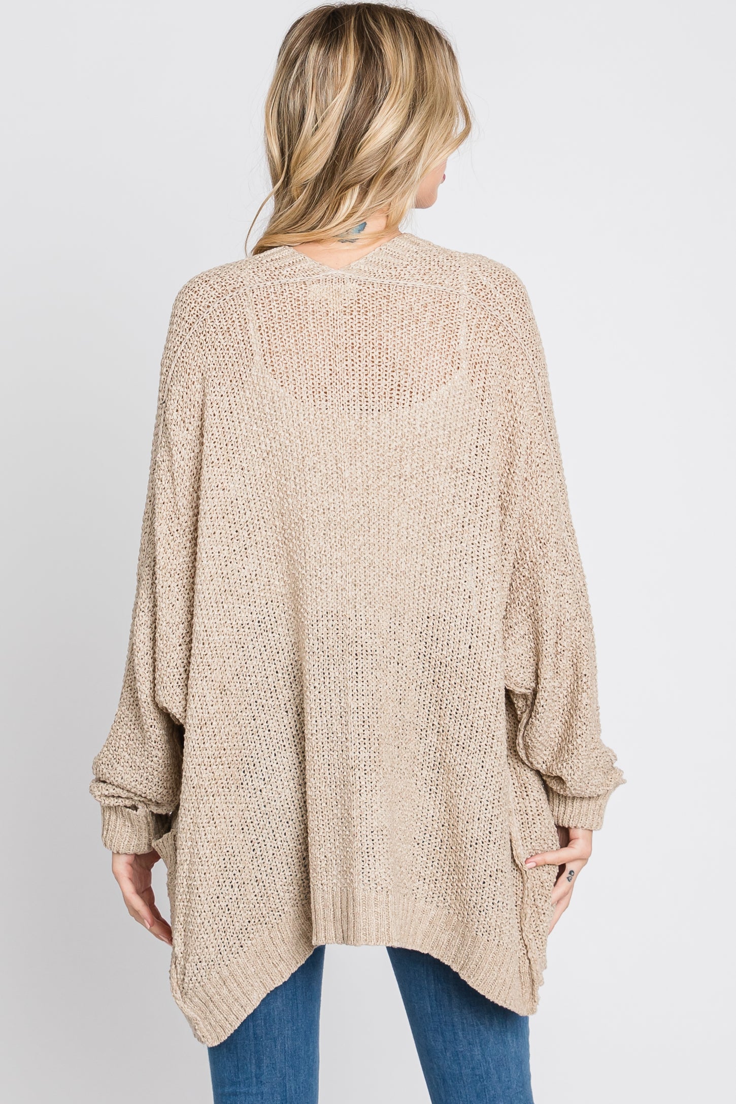 woman wearing a beige oversized knitted cardigan sweater with a loose fit and batwing sleeves