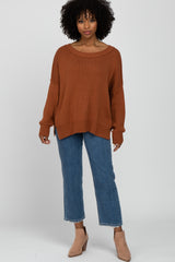 woman wearing a rust oversized knit sweater and blue cropped jeans with beige ankle boots