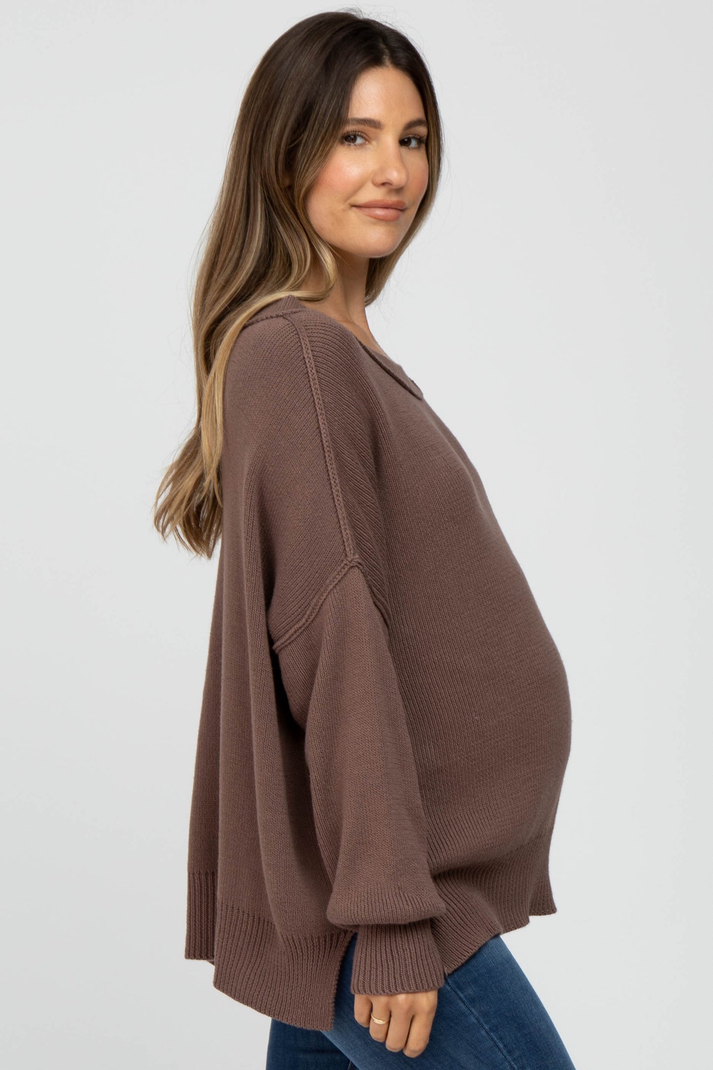 woman wearing a brown oversized maternity sweater and showing her baby bump
