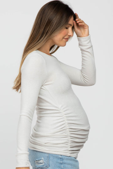 woman wearing a white long sleeve maternity top with side ruching and a visible baby bump