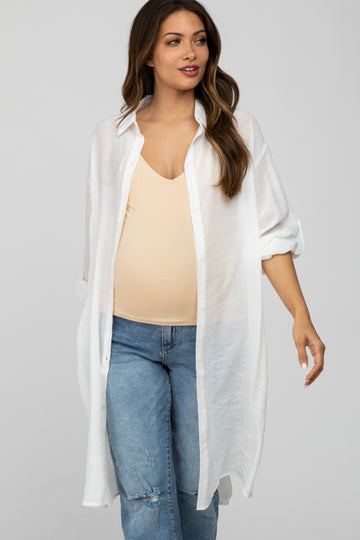 woman wearing a white oversized button-up maternity shirt over a light beige tank top and distressed jeans, showing her baby bump