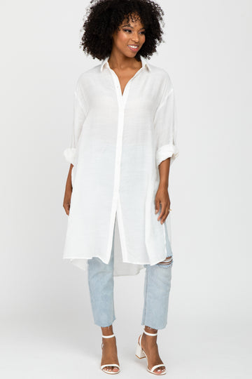 woman wearing a white long sleeve button-up tunic top with rolled sleeves and light blue distressed jeans