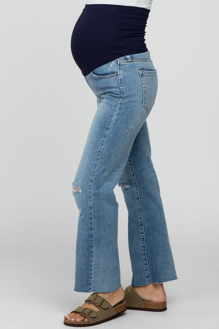 pregnant woman wearing distressed light wash maternity flare jeans with a navy blue belly band