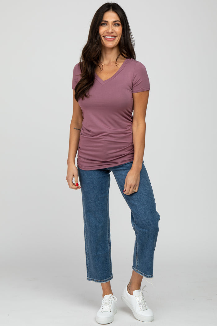 woman wearing a mauve short sleeve v-neck top and high-waisted blue jeans with white sneakers