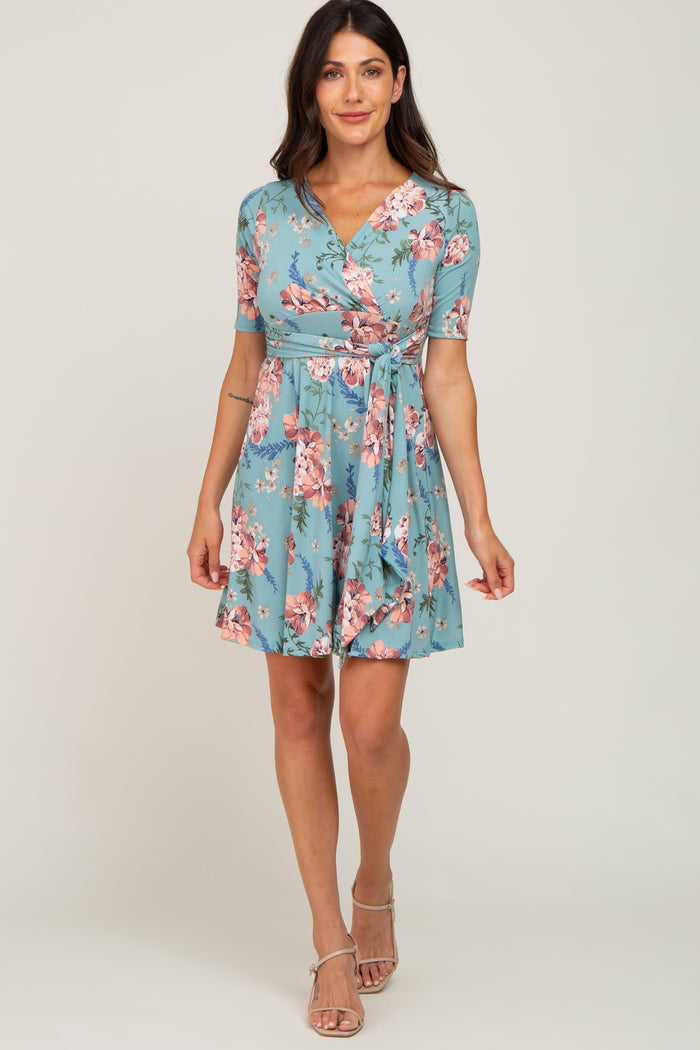 woman wearing a turquoise floral wrap dress with short sleeves and a tie waist