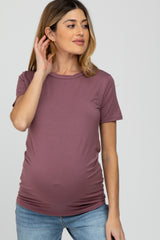 woman wearing a mauve short sleeve maternity top and highlighting her baby bump