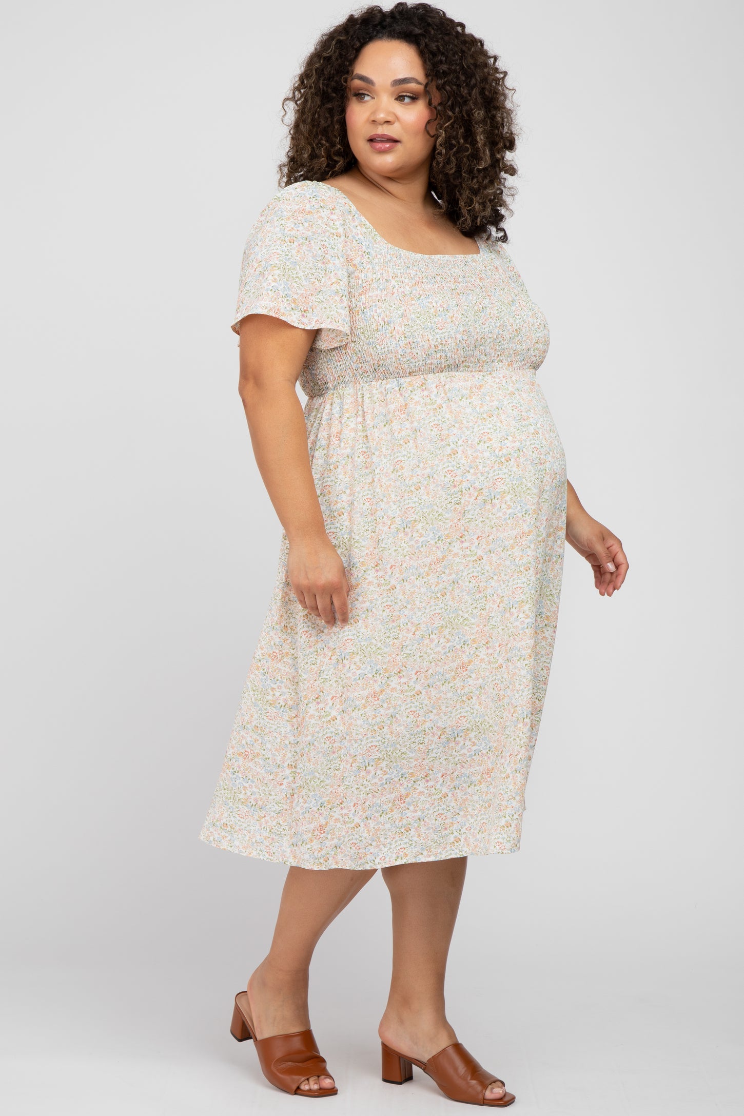 woman wearing a floral print maternity plus dress with short sleeves and a baby bump_visible