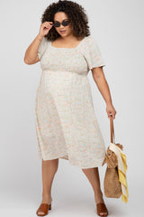 woman wearing a floral maternity plus dress with short sleeves and a square neckline, holding a bag and wearing sunglasses
