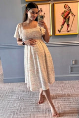 woman wearing a floral print maternity dress with short sleeves and holding her baby bump