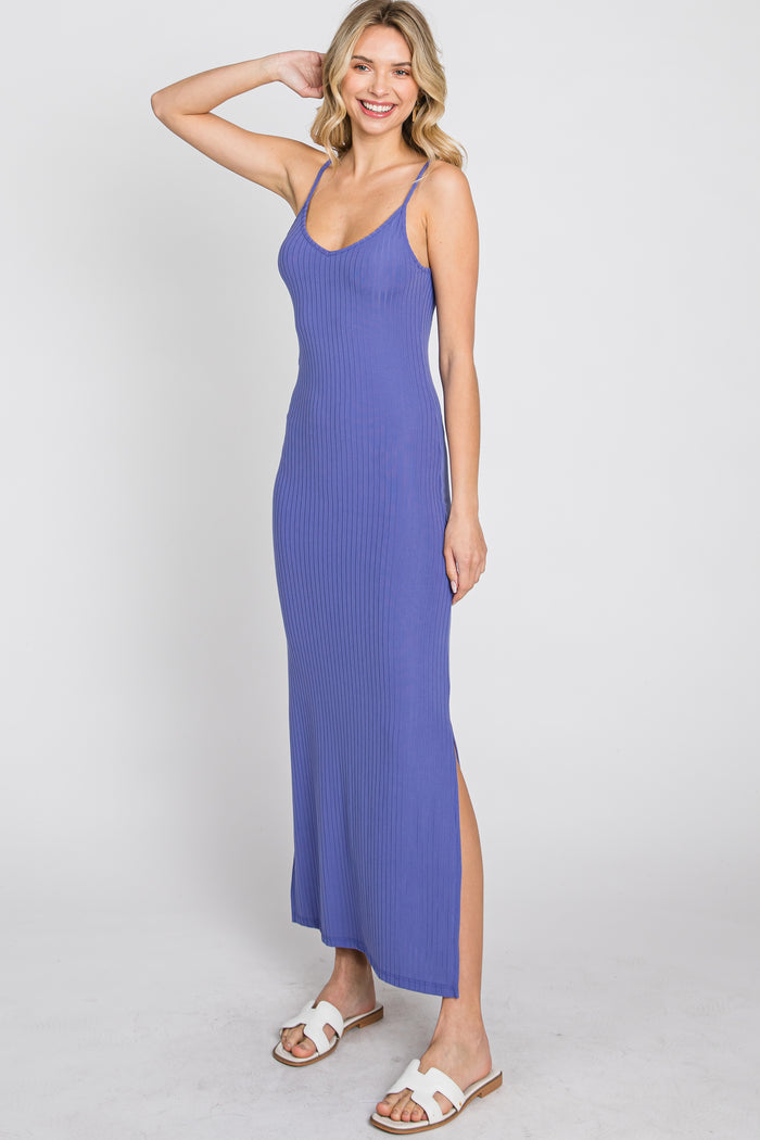 woman wearing a royal blue ribbed maxi dress with thin straps and side slit, standing and smiling