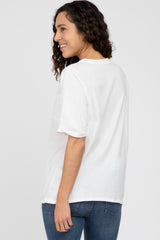 woman wearing a white short sleeve t-shirt and blue jeans, standing sideways with a slight smile
