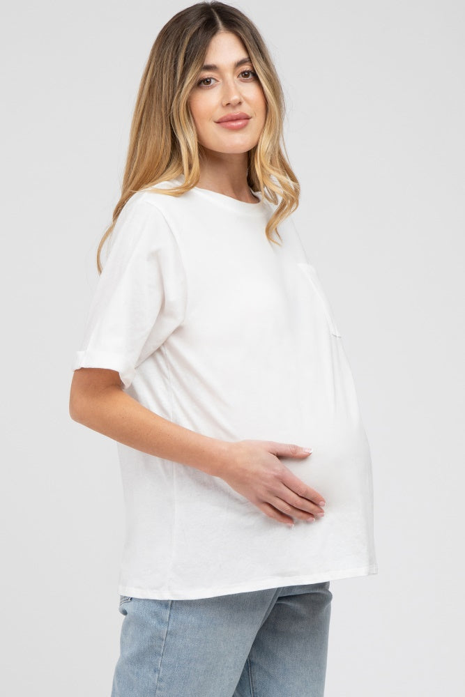 woman wearing a white short sleeve maternity top and holding her baby bump