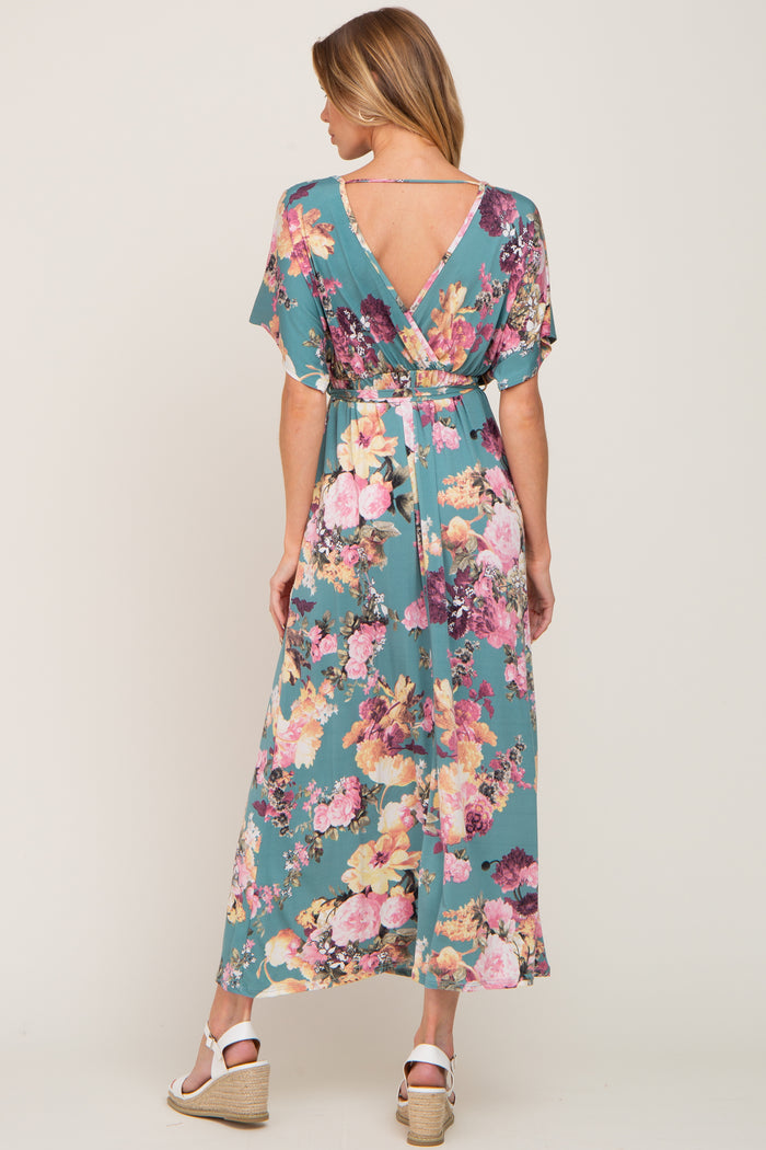 Woman from behind wearing a teal floral maxi dress with a v-back and white wedge sandals