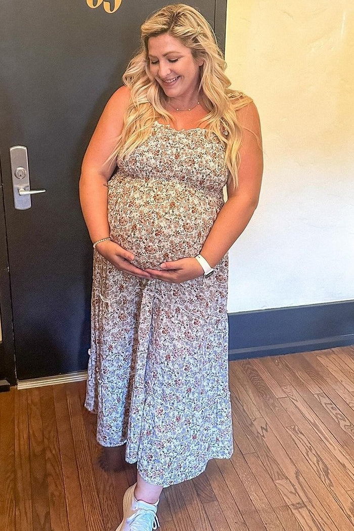 woman wearing a floral maternity maxi dress and holding her baby bump