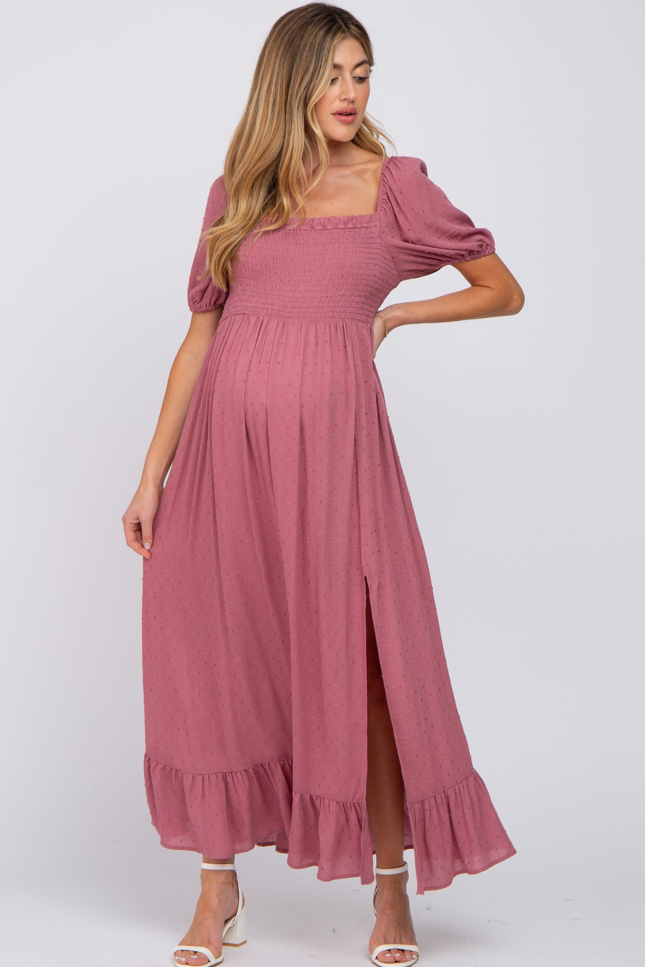 woman wearing a dusty rose maternity maxi dress with puff sleeves and a side slit, showcasing her baby bump