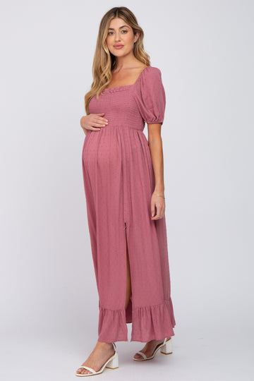 woman wearing a dusty rose maternity dress with puff sleeves and a leg slit, holding her baby bump
