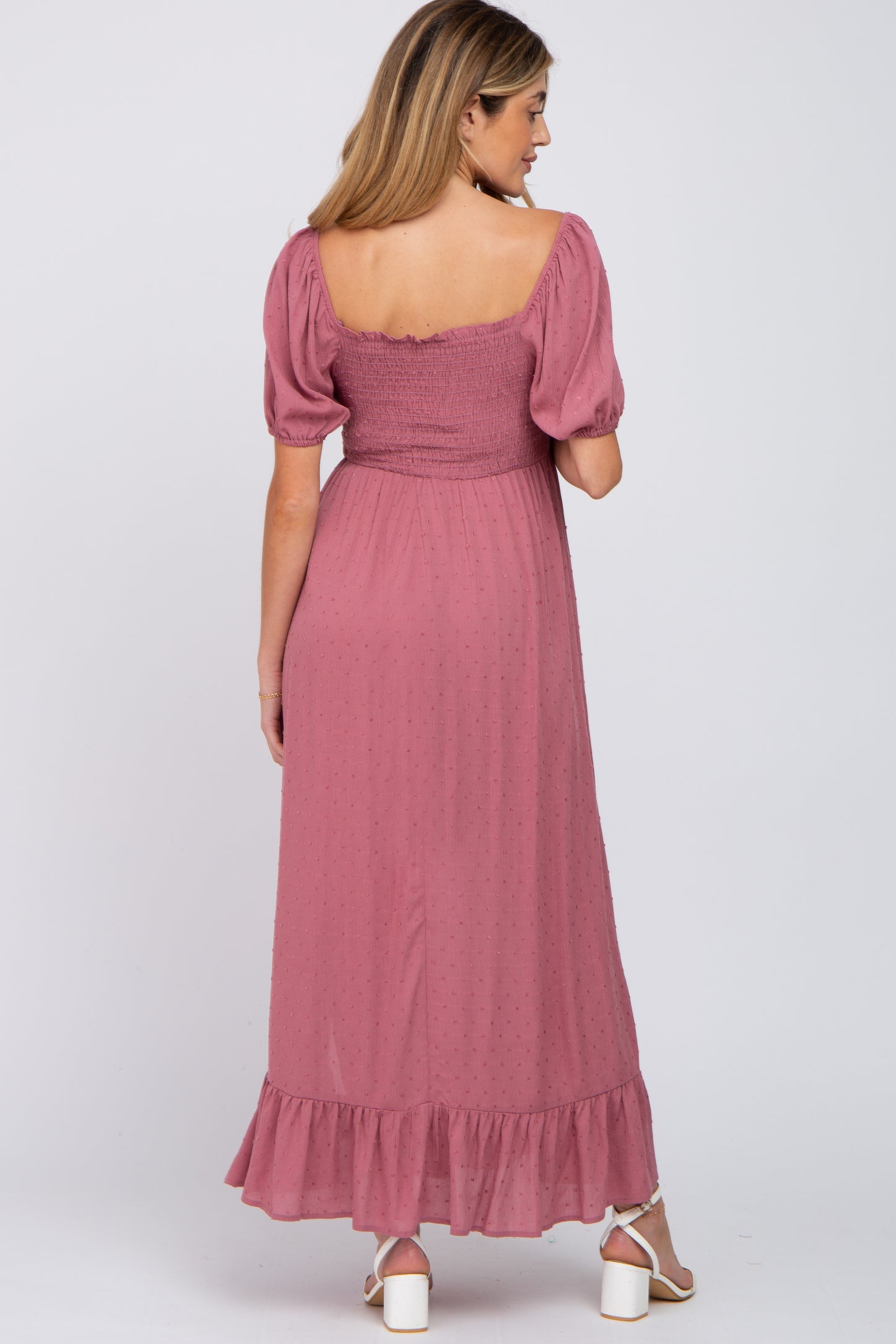 woman wearing a mauve maternity maxi dress with puff sleeves and ruffle hem, showing her back