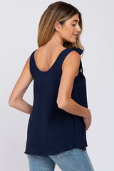 woman wearing a navy blue sleeveless maternity top with shoulder ties and a visible baby bump