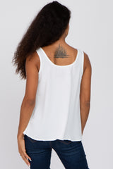 woman wearing a white sleeveless top, showing a tattoo on her back, paired with dark denim jeans