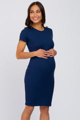 woman wearing a navy blue short sleeve maternity dress and holding her baby bump