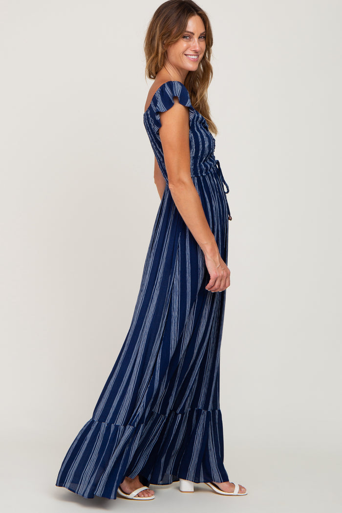 woman wearing a navy off-the-shoulder maxi dress with white stripes and a flared bottom