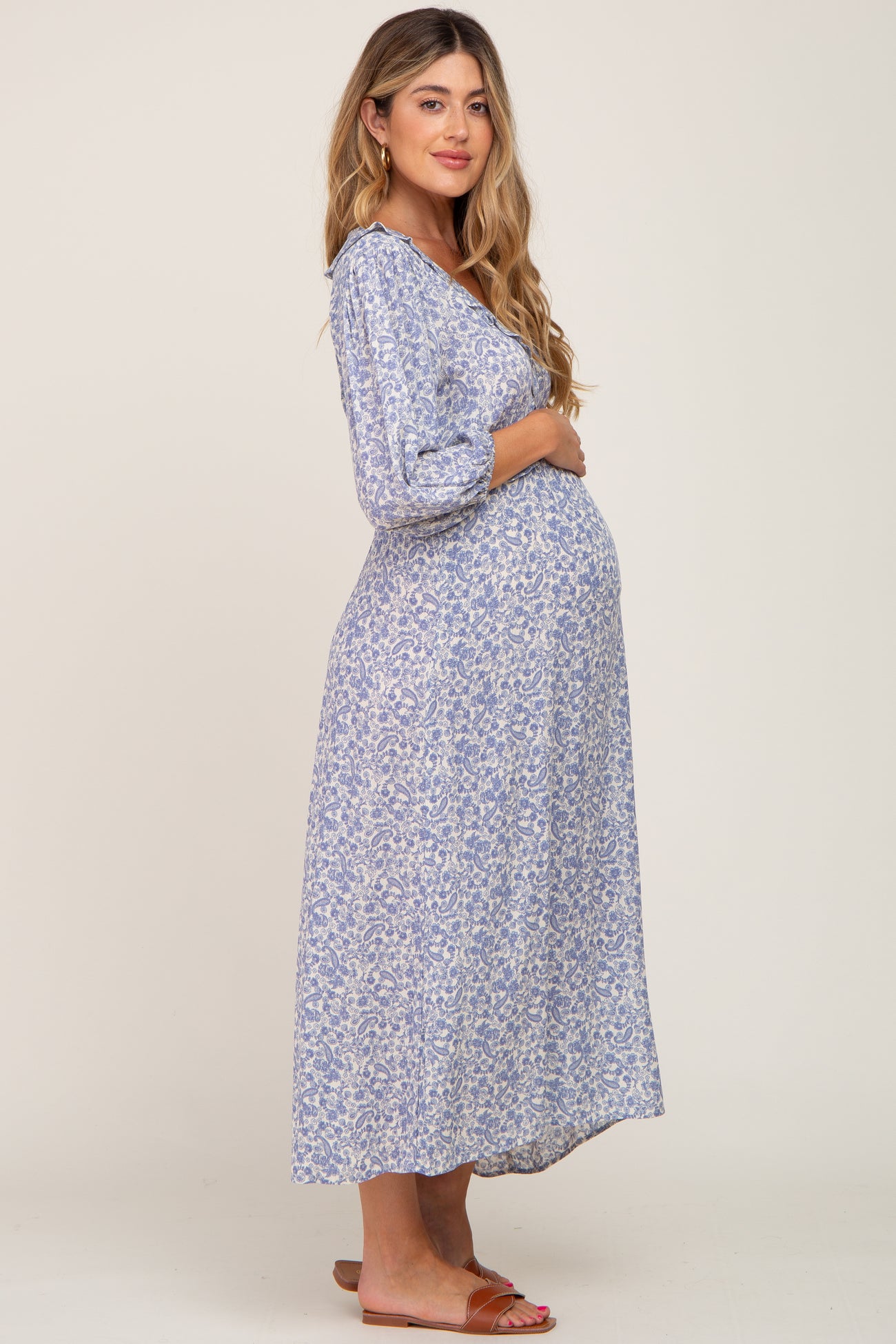 woman wearing a floral print maternity maxi dress and holding her baby bump