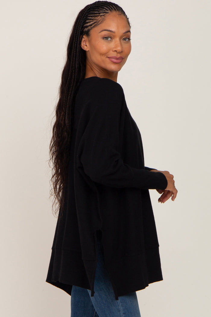 woman wearing a black oversized sweater with side slits and long sleeves