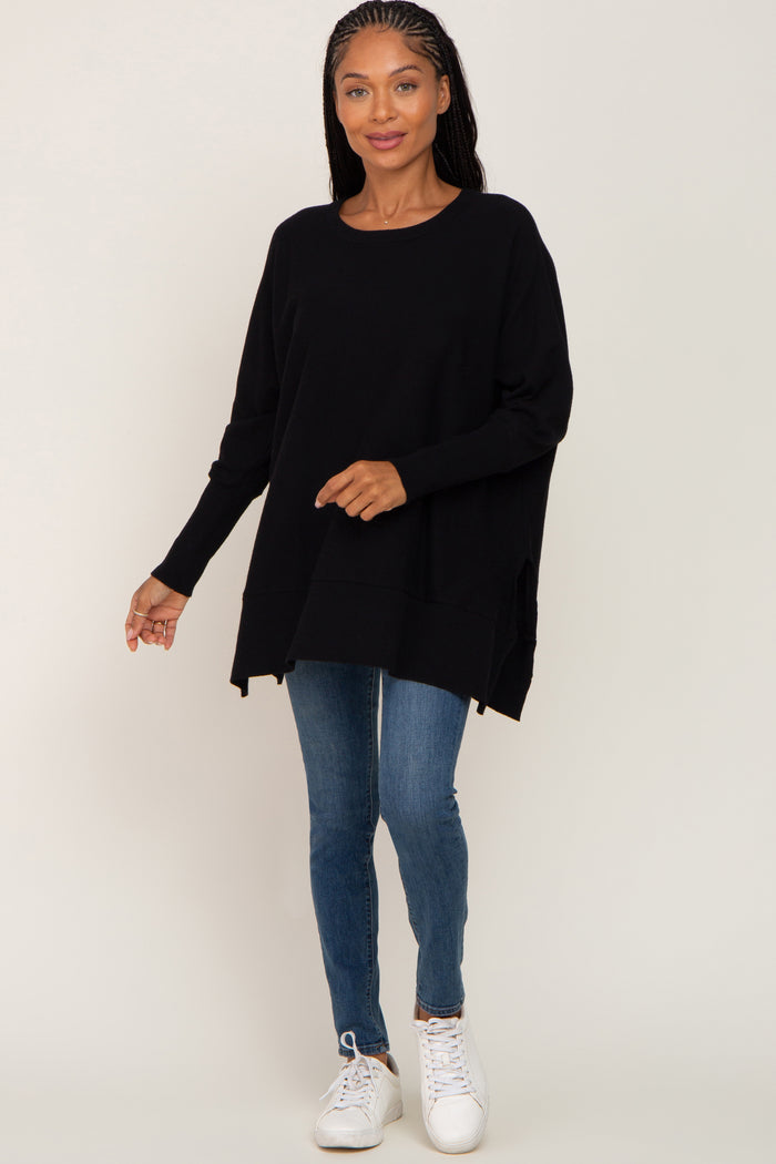 woman wearing oversized black crewneck sweater with blue skinny jeans and white sneakers