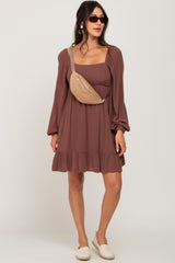woman wearing a brown square neck long sleeve dress with a ruffled hem and a tan crossbody bag